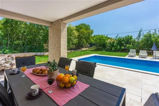 Covered patio dining area overlooking backyard pool