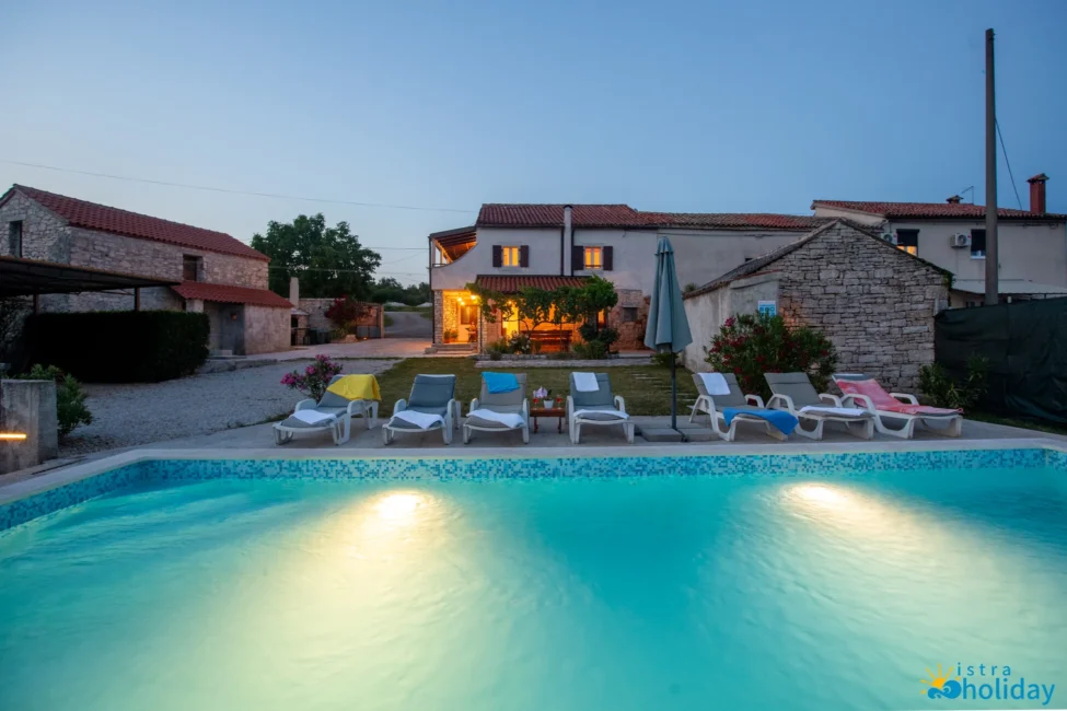 Charming villa with pool and lounge chairs at dusk.