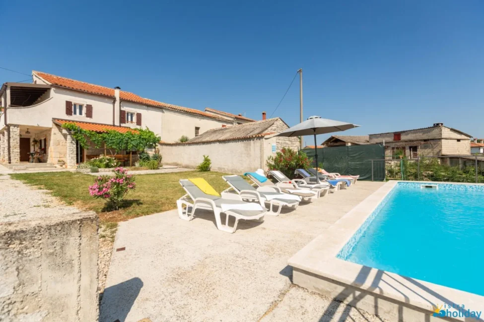 Sun loungers by outdoor pool and house.