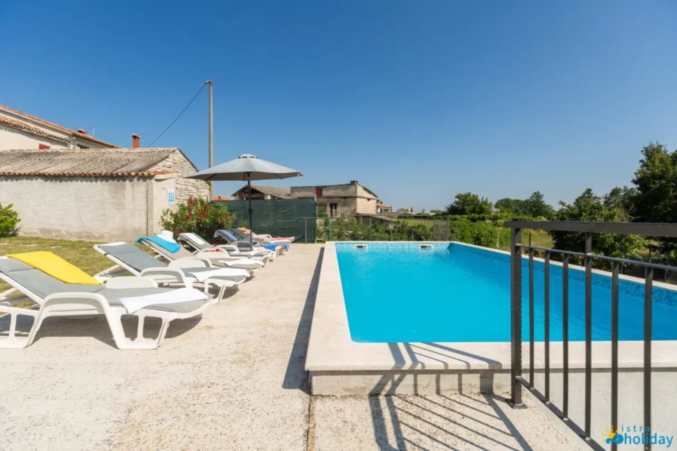 Outdoor pool with sun loungers and umbrella.
