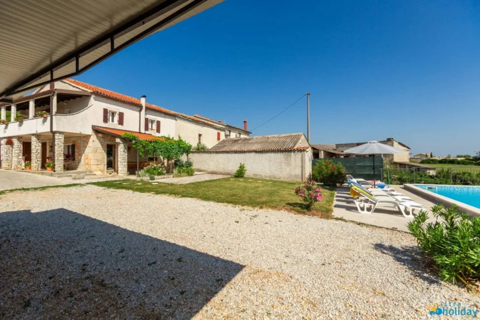 Stone villa with pool and sun loungers.