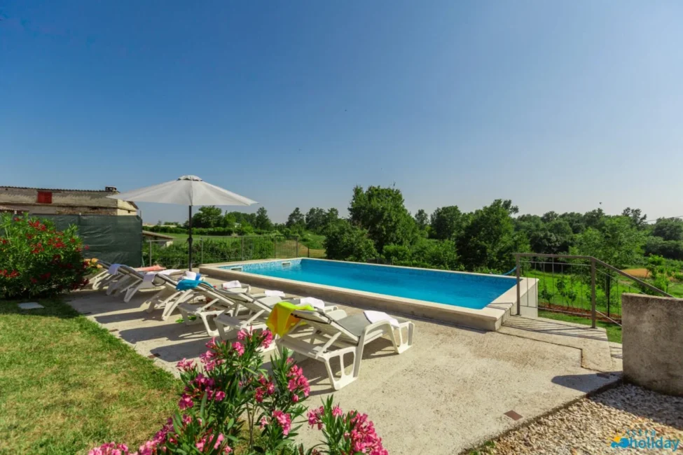 Sunny poolside with loungers and countryside view.