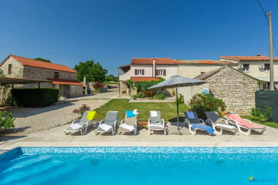 Cozy villa with pool and sun loungers outside.