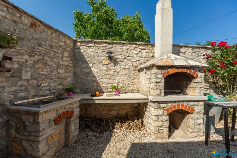Stone outdoor kitchen with sink and pizza oven