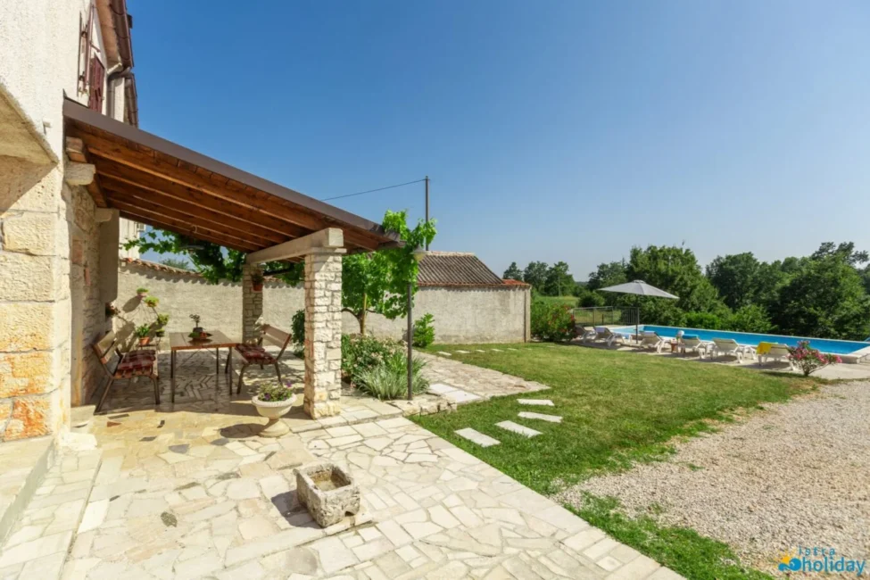 Stone patio with outdoor seating near swimming pool