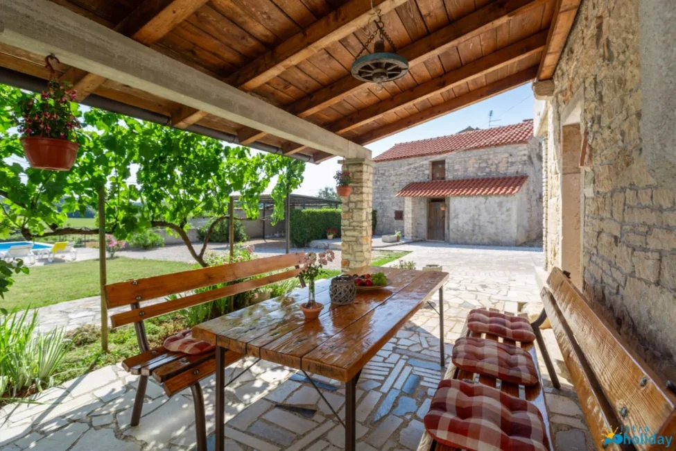 Rustic patio with wooden table and chairs.