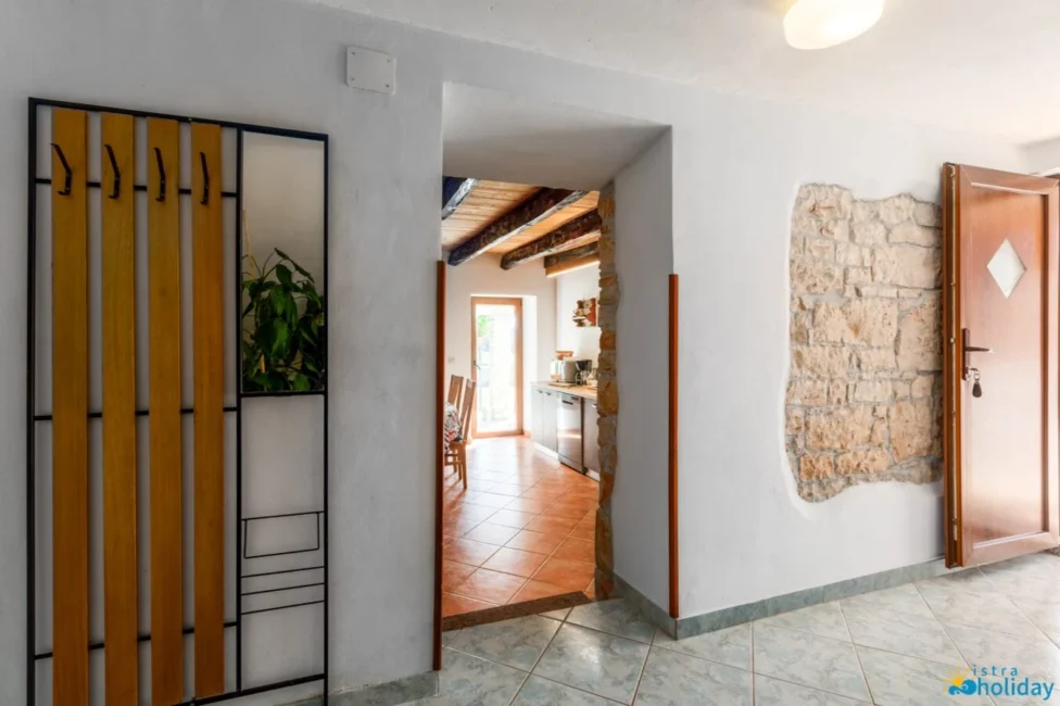 Rustic hallway entrance to bright kitchen with wooden beams.