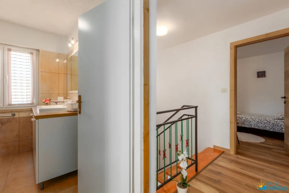 Bathroom, hallway, and bedroom with wooden flooring.