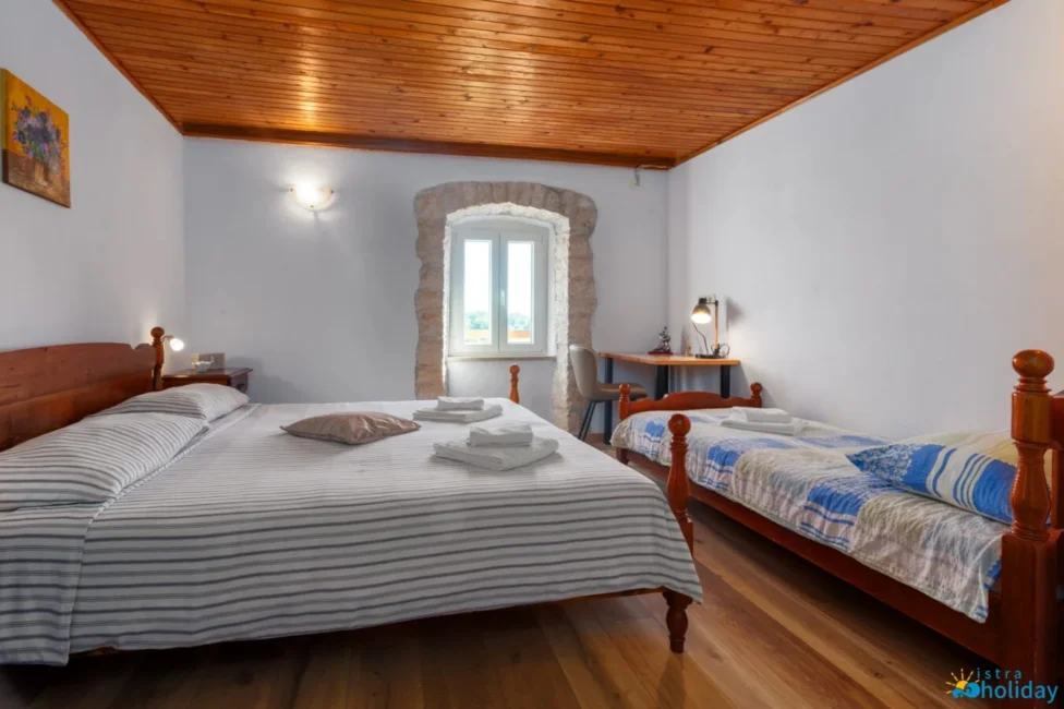 Cozy bedroom with two beds and wooden ceiling.