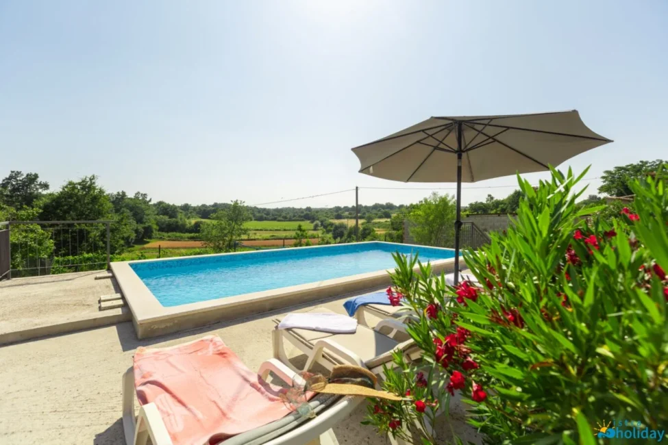 Outdoor pool with countryside view and lounge chairs.