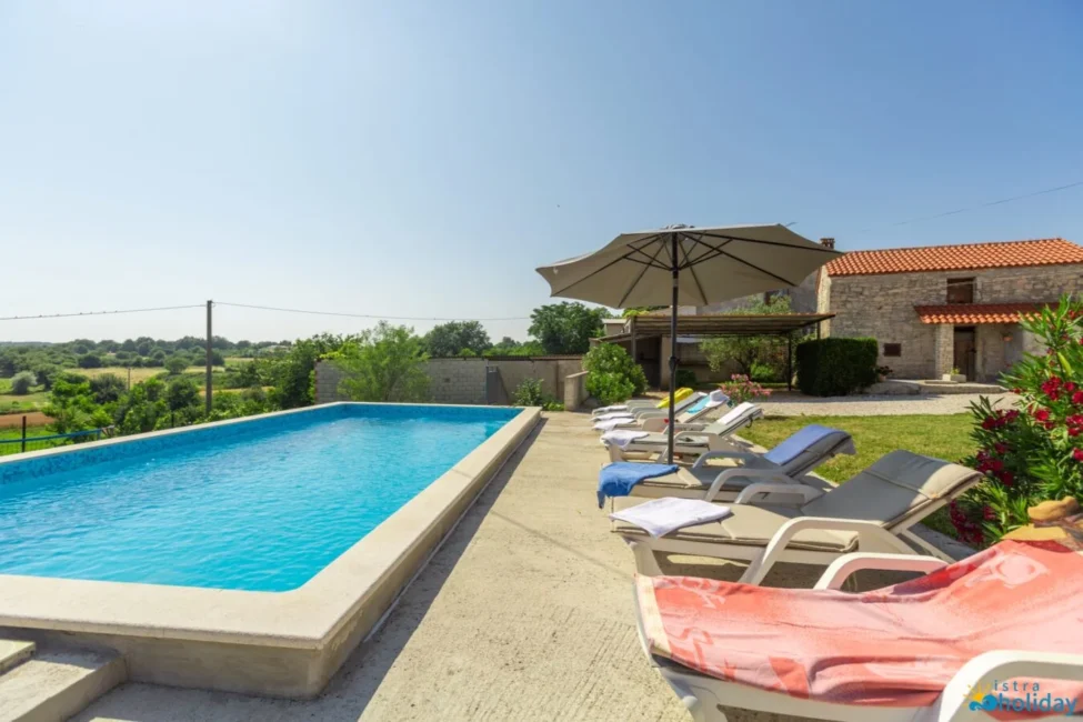 Swimming pool with lounge chairs and umbrella.