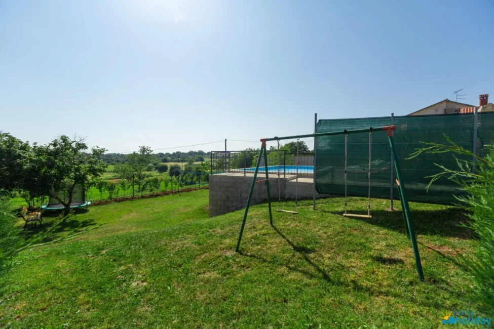 Backyard with swings and pool in sunny landscape.